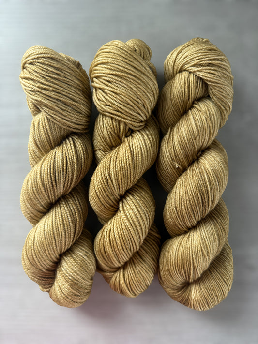 Three skeins of ethically sourced, hand-dyed golden merino wool yarn, "Adirondack Chair" colorway.