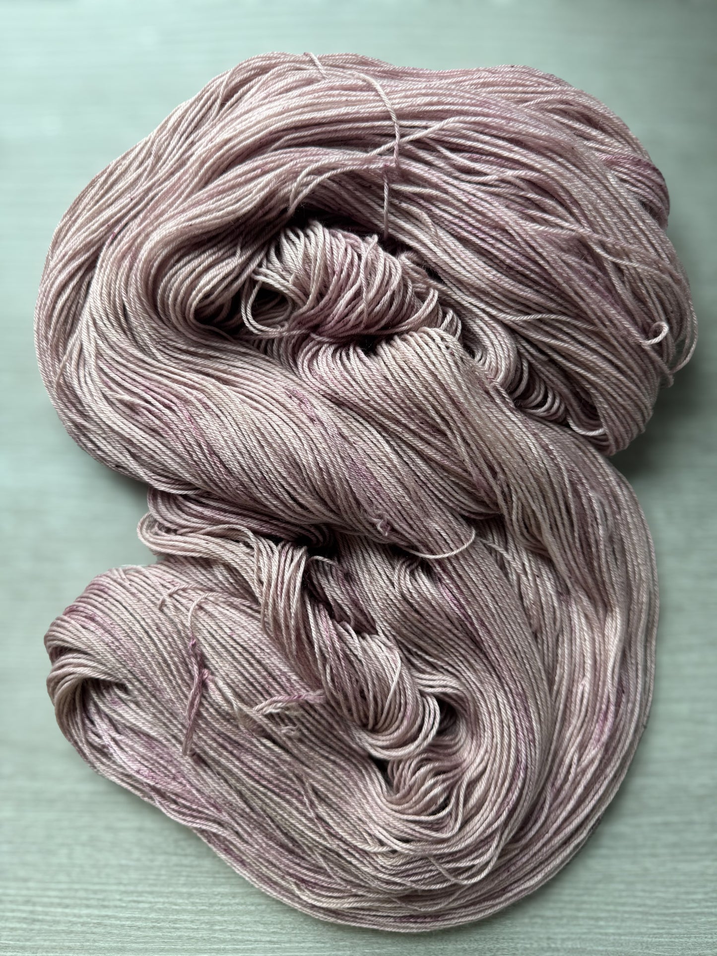 Coiled skein of pinkish yarn on a light gray background