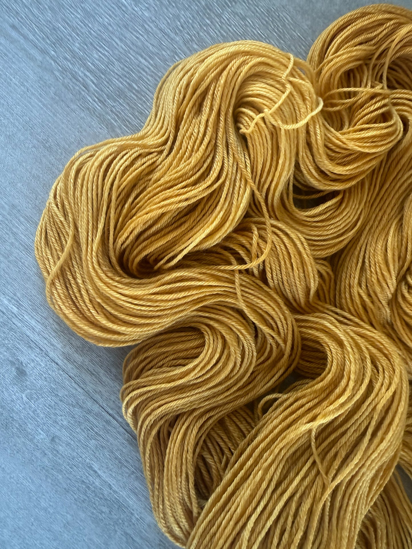 Hand-dyed "None Of Your Beeswax" golden yellow merino wool yarn, ethically sourced.