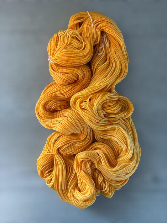 Soleil bright golden yellow hand-dyed ethically sourced merino wool yarn skein, radiating warmth.