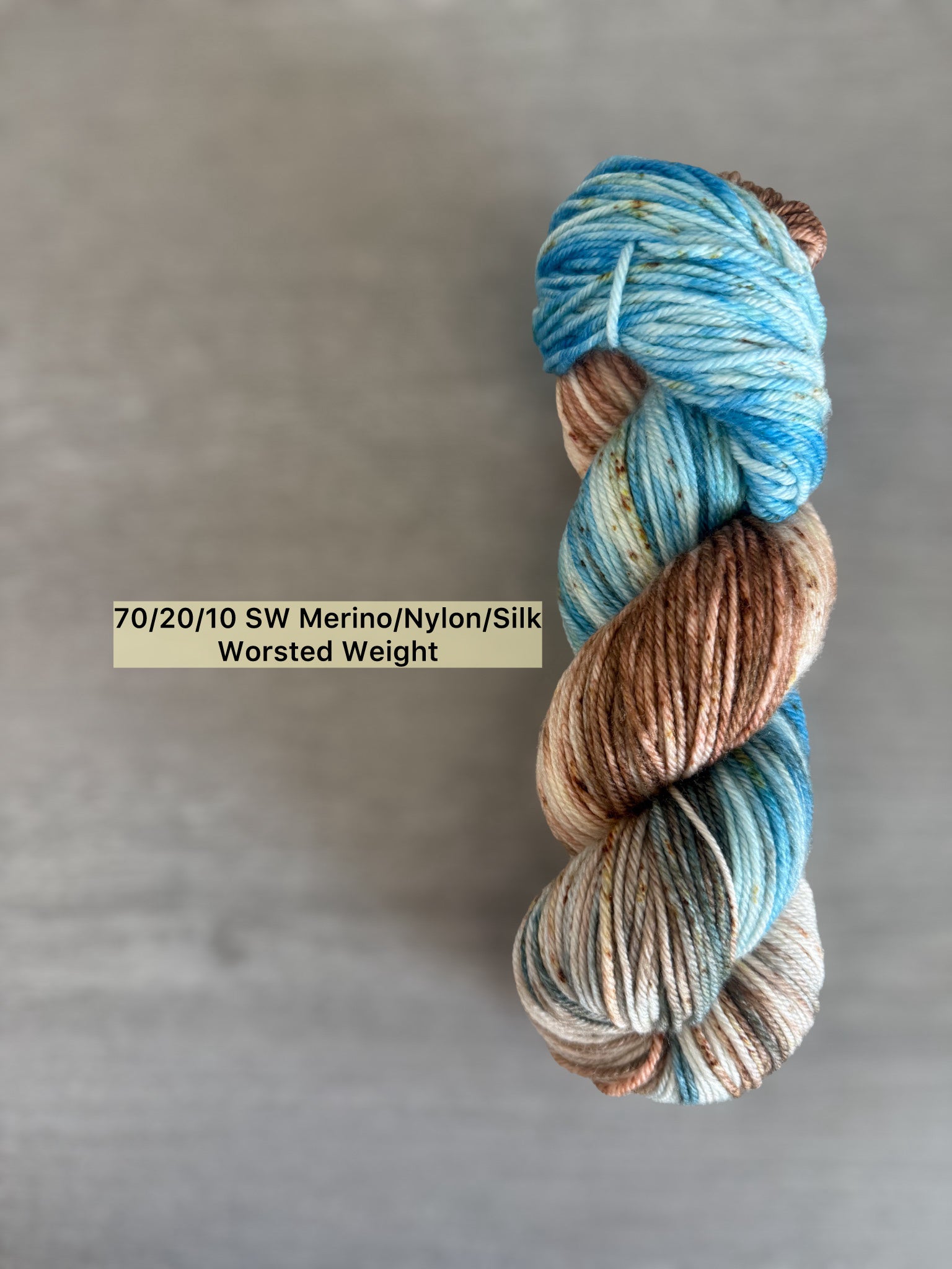 Hand-dyed variegated merino wool yarn in robins egg blue, caramel, and brown speckles.