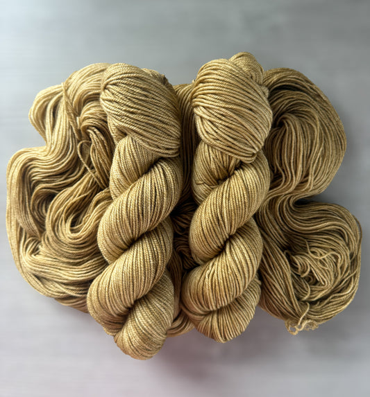Ethically sourced "Adirondack Chair" hand-dyed merino wool yarn in warm golden tones.