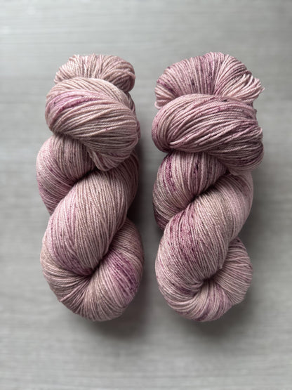 Two skeins of pink yarn on a gray background