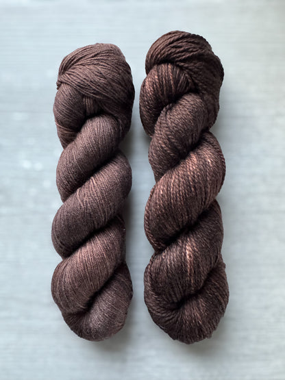 Two skeins of brown yarn on a light gray background