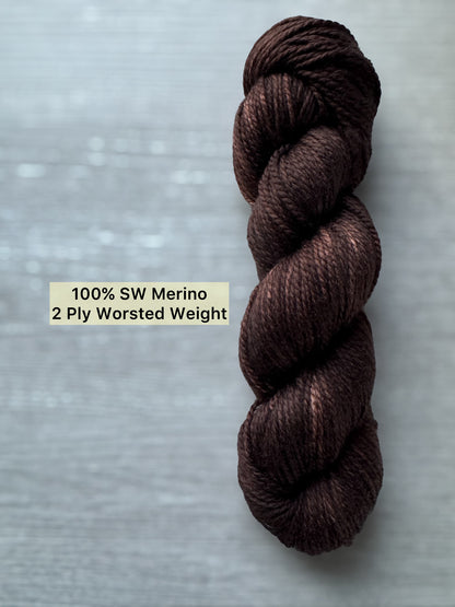 Brown skein of yarn labeled '100% SW Merino 2 Ply Worsted Weight' on a gray background