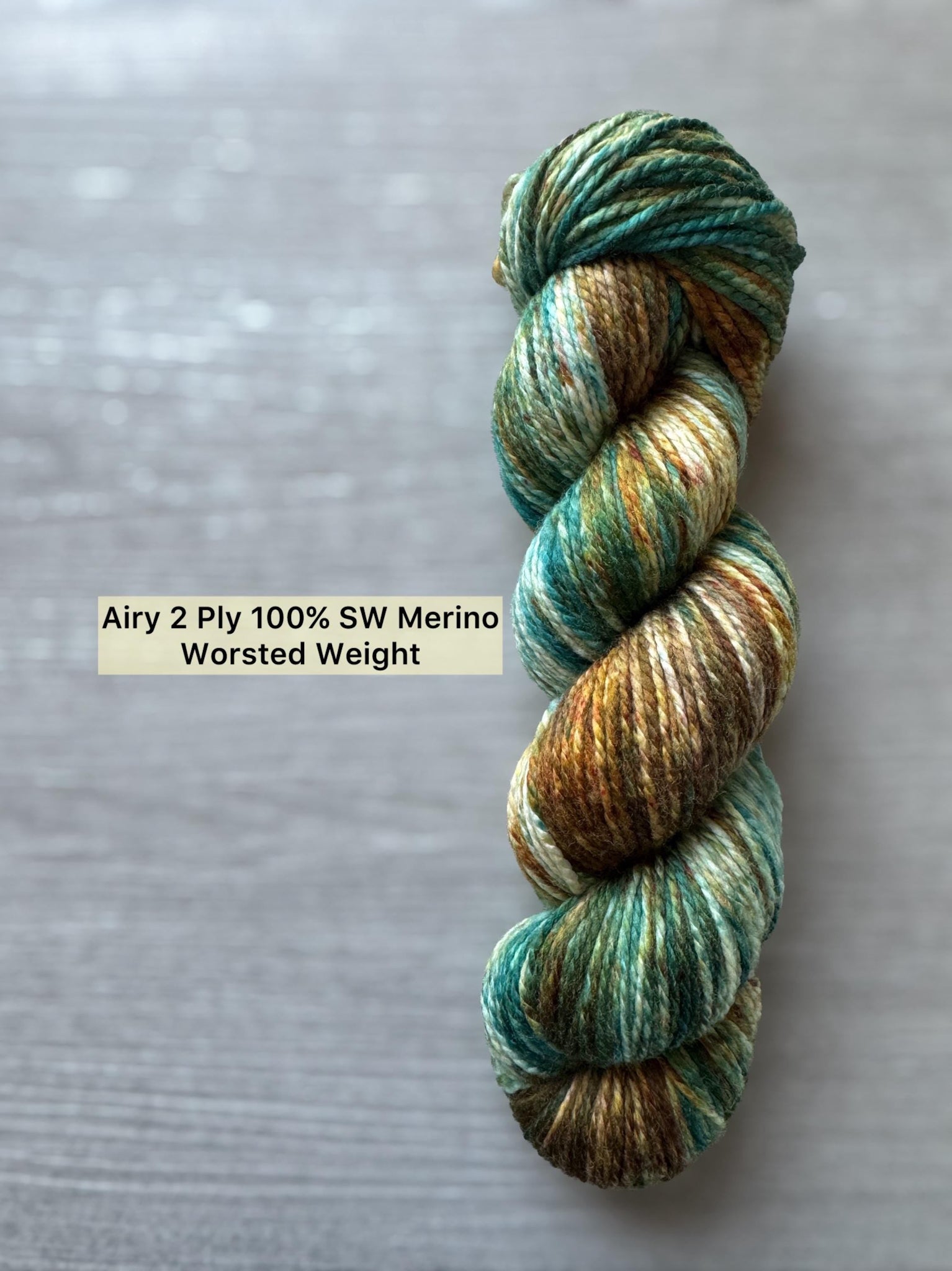 Hand-dyed Copper Patina ethically sourced merino wool yarn skein, featuring teal, brown, and cream hues.