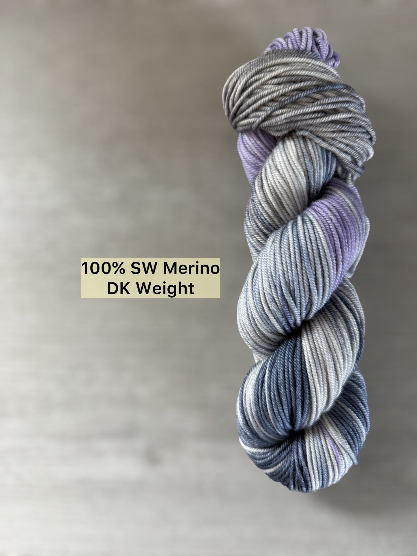 Hand-dyed ethically sourced merino wool yarn in deep blue, soft lilac, and muted gray, DK weight.