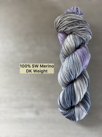 Hand-dyed ethically sourced merino wool yarn in deep blue, soft lilac, and muted gray, DK weight.