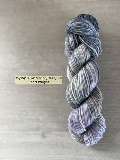 Hand-dyed ethically sourced merino wool yarn in deep blue, soft lilac, and muted gray, sport weight.