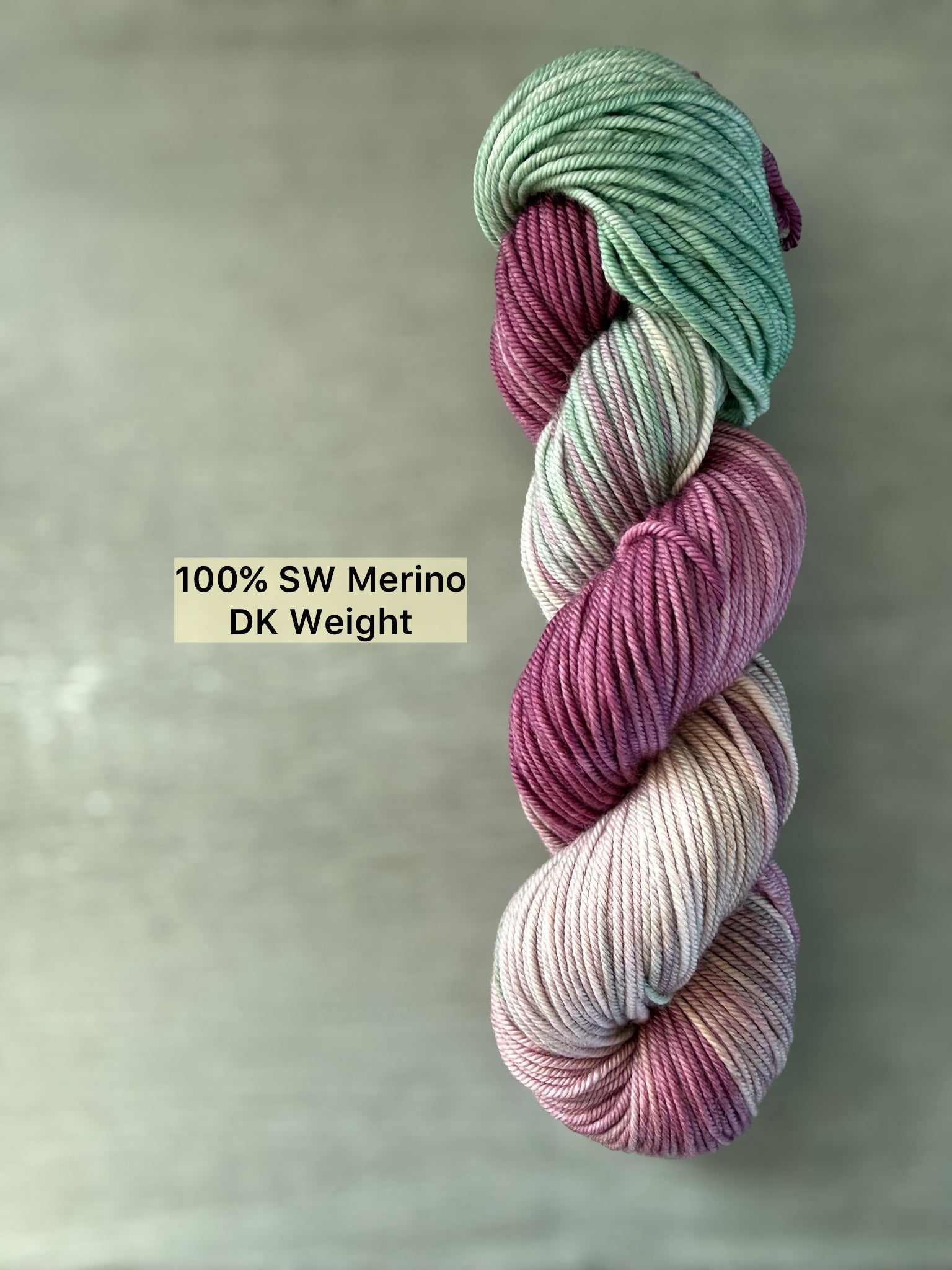 Ethically sourced DK weight merino wool yarn in plum, ivory, and sage green, hand-dyed with subtle transitions.