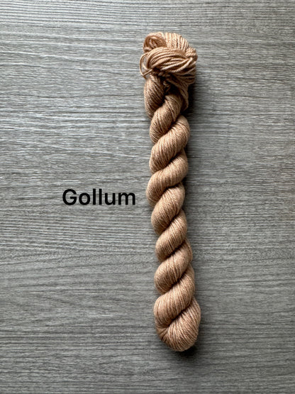 Beige skein of yarn labeled 'Gollum' on a gray wooden surface