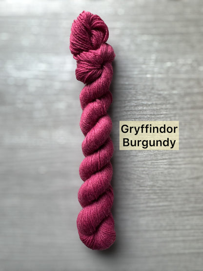 Burgundy skein of yarn labeled 'Gryffindor Burgundy' on a gray background