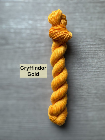 Yellow yarn skein labeled 'Gryffindor Gold' on a gray background
