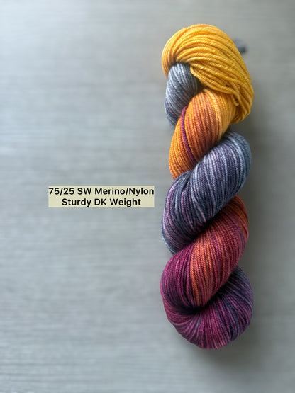 Ethically sourced Malabar Squirrel hand-dyed merino wool yarn in variegated blues, golden yellow, and burgundy.