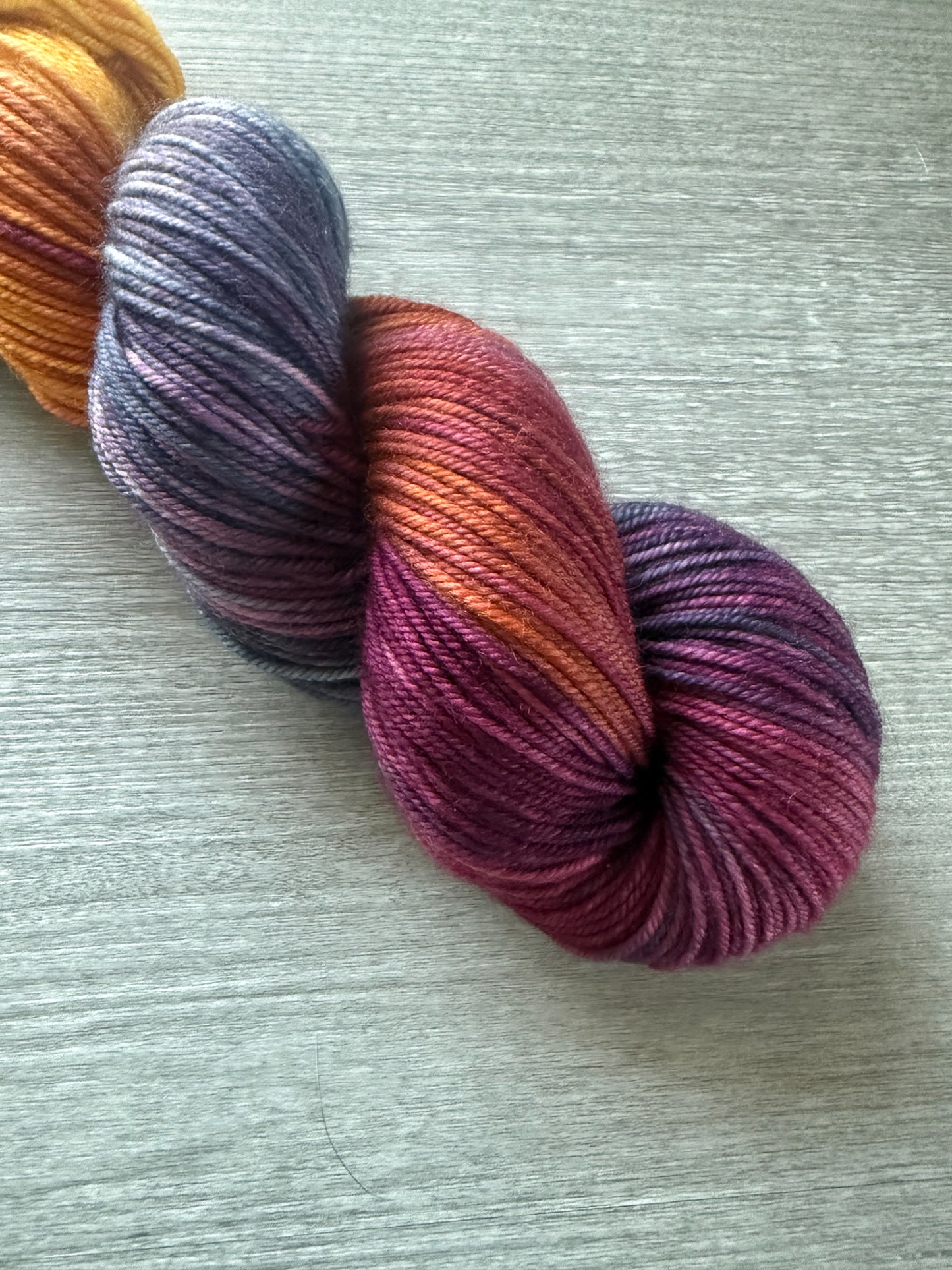 Ethically sourced Malabar Squirrel hand-dyed merino wool yarn with variegated blues, golden yellow, and burgundy.