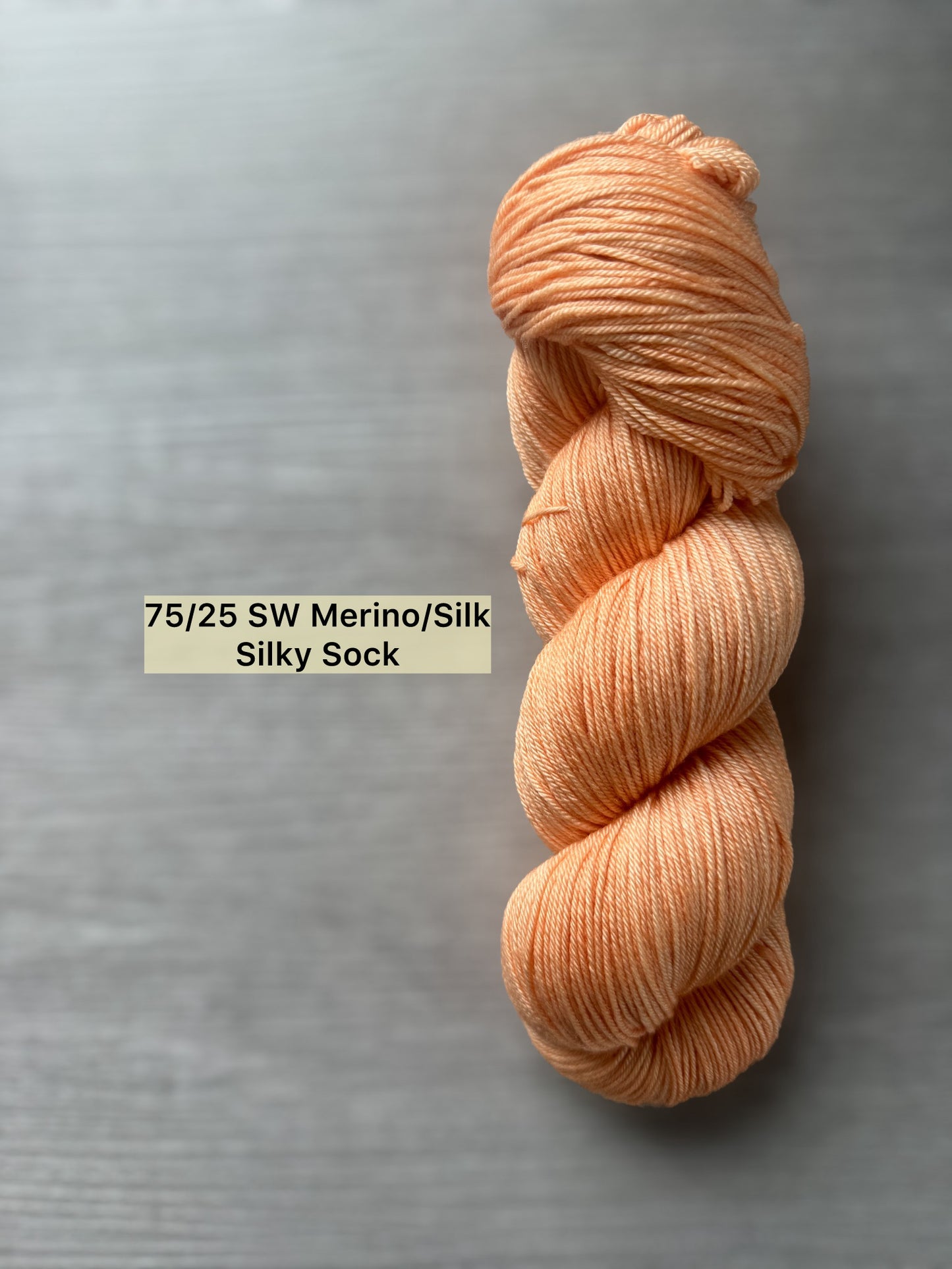 Ethically sourced "Melon Dollar Smile" hand-dyed merino wool yarn in a vibrant coral-peach hue.