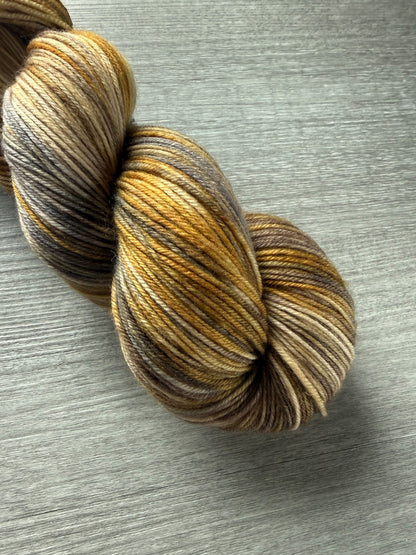 Hand-dyed Mesa merino wool yarn in variegated beige, charcoal, taupe, and toasted ocher.