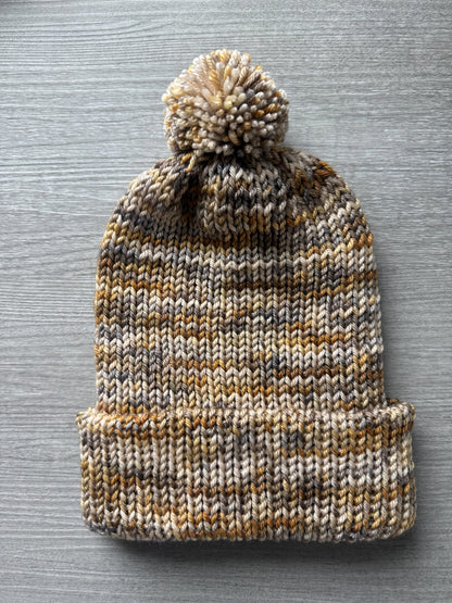 Hand-knitted beanie from Mesa Artisan ethically sourced merino wool yarn, featuring beige, charcoal, taupe, and ocher.