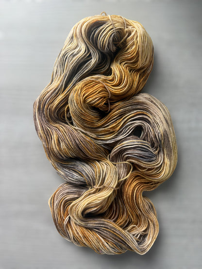 Hand-dyed Mesa ethically sourced merino wool yarn in variegated beige, charcoal, taupe, and toasted ocher.