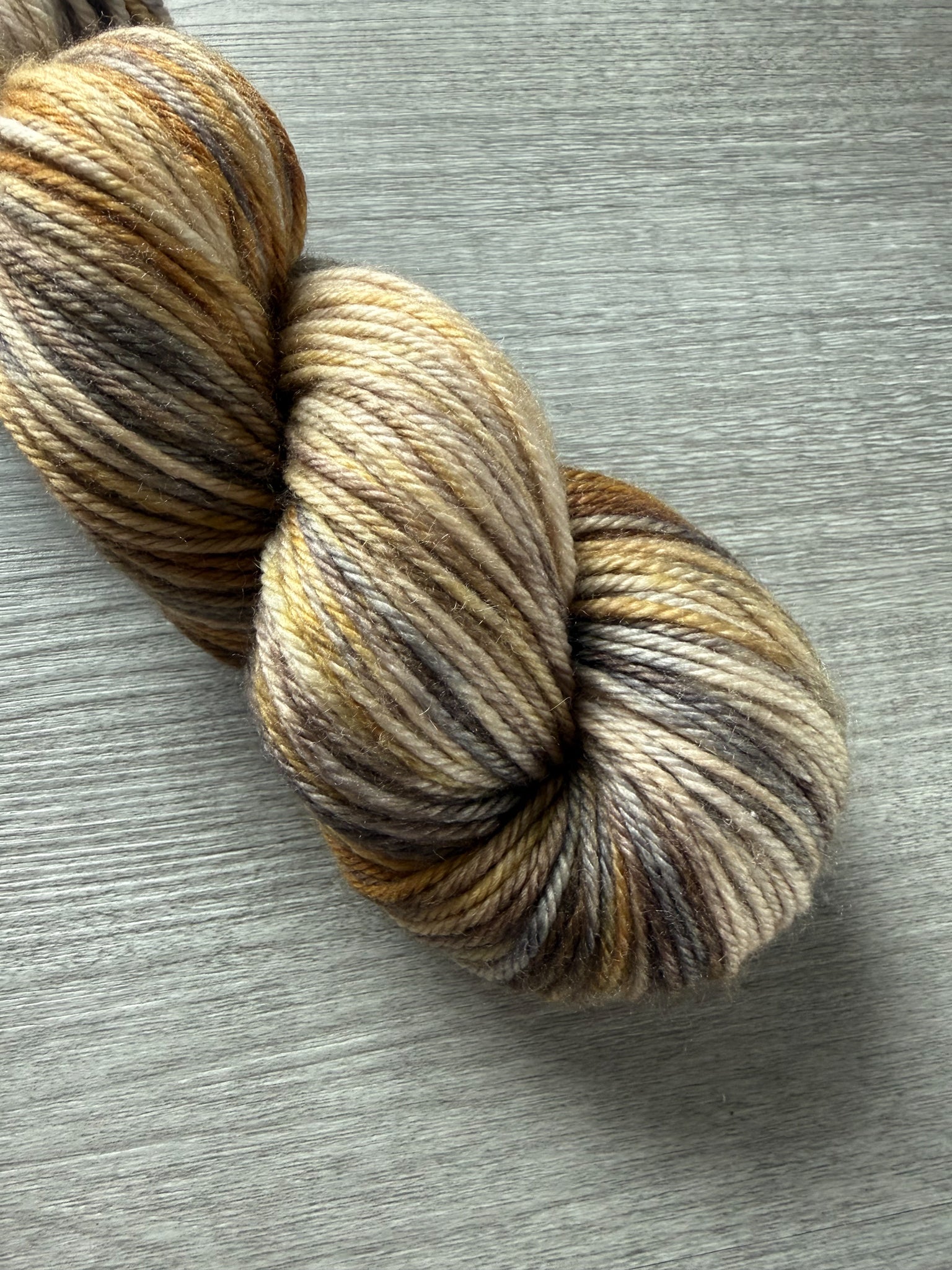 Hand-dyed Mesa merino wool yarn in variegated beige, charcoal, taupe, and toasted ocher.