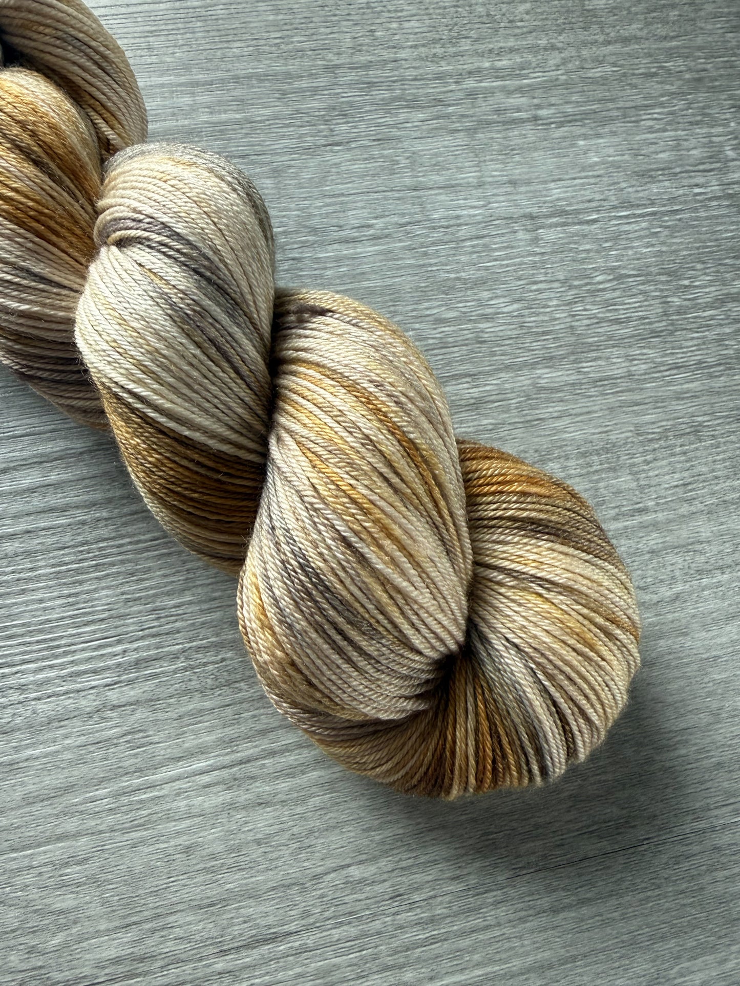 Hand-dyed Mesa merino wool yarn in variegated beige, charcoal, taupe, and toasted ocher.