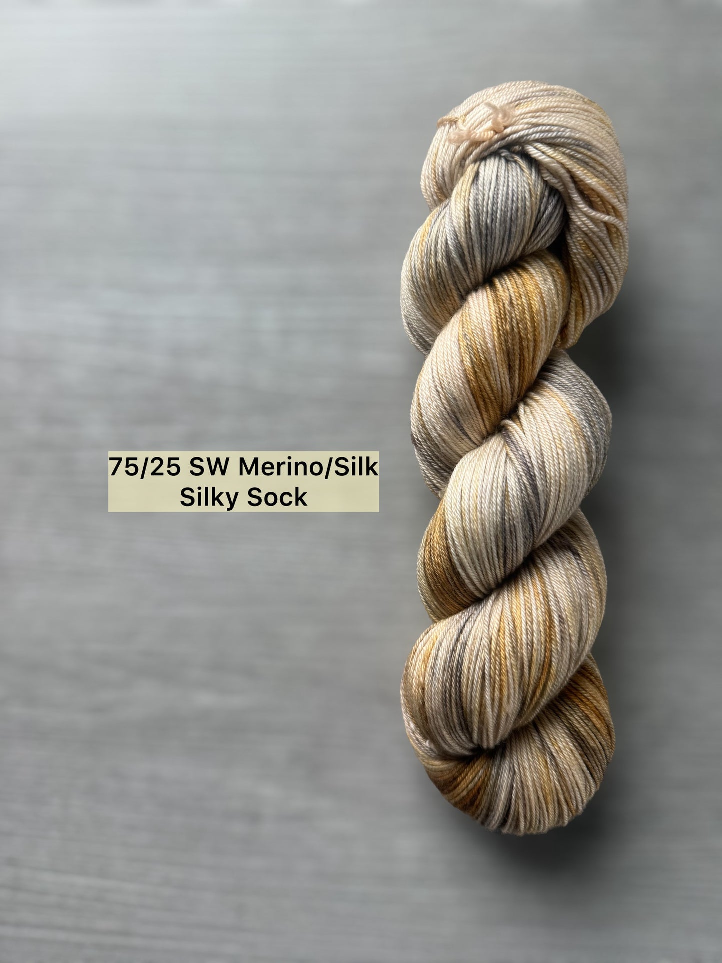Hand-dyed Mesa ethically sourced merino/silk yarn in beige, charcoal, taupe, and toasted ocher.