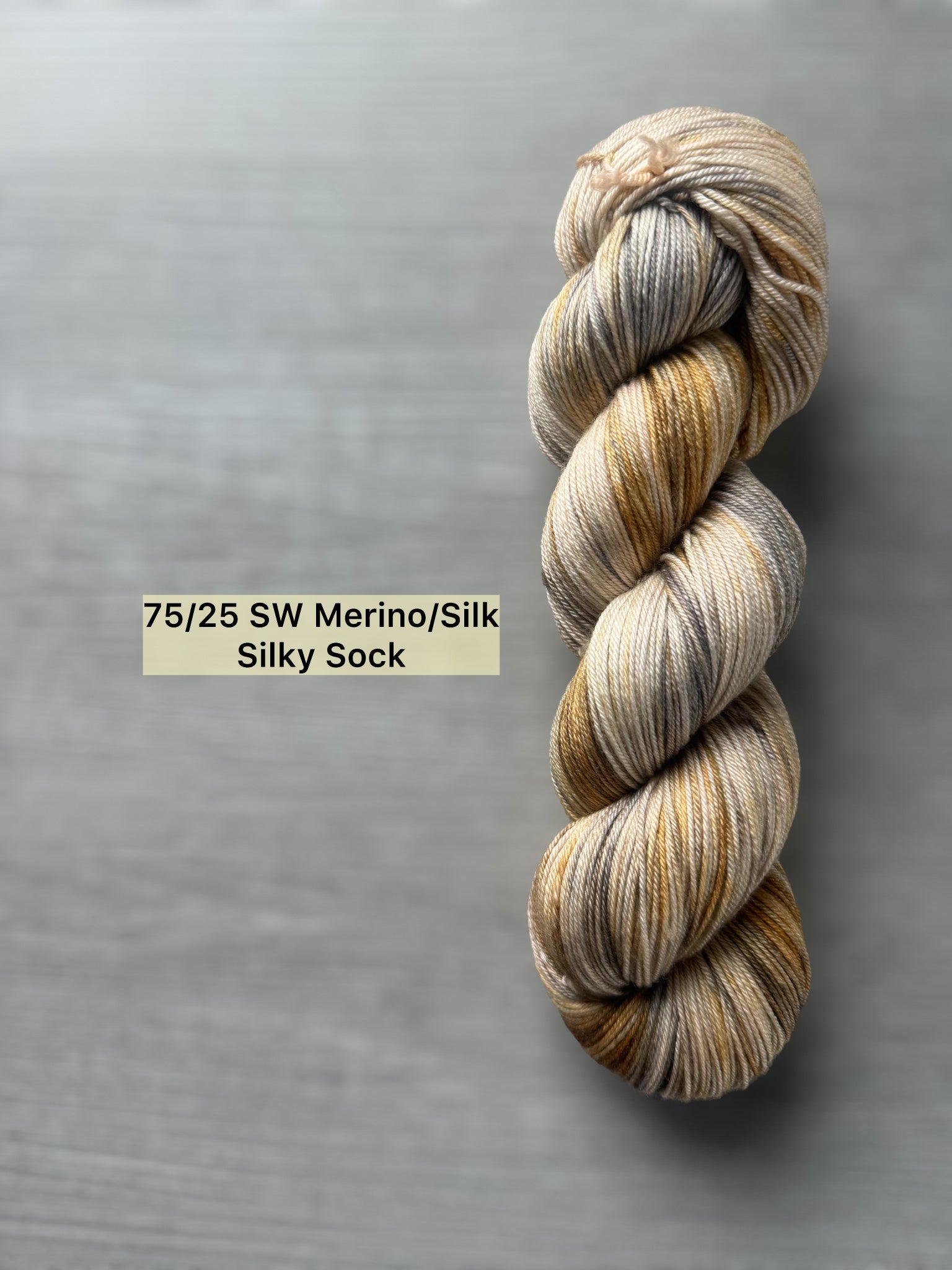 Hand-dyed Mesa ethically sourced merino/silk yarn in beige, charcoal, taupe, and toasted ocher.