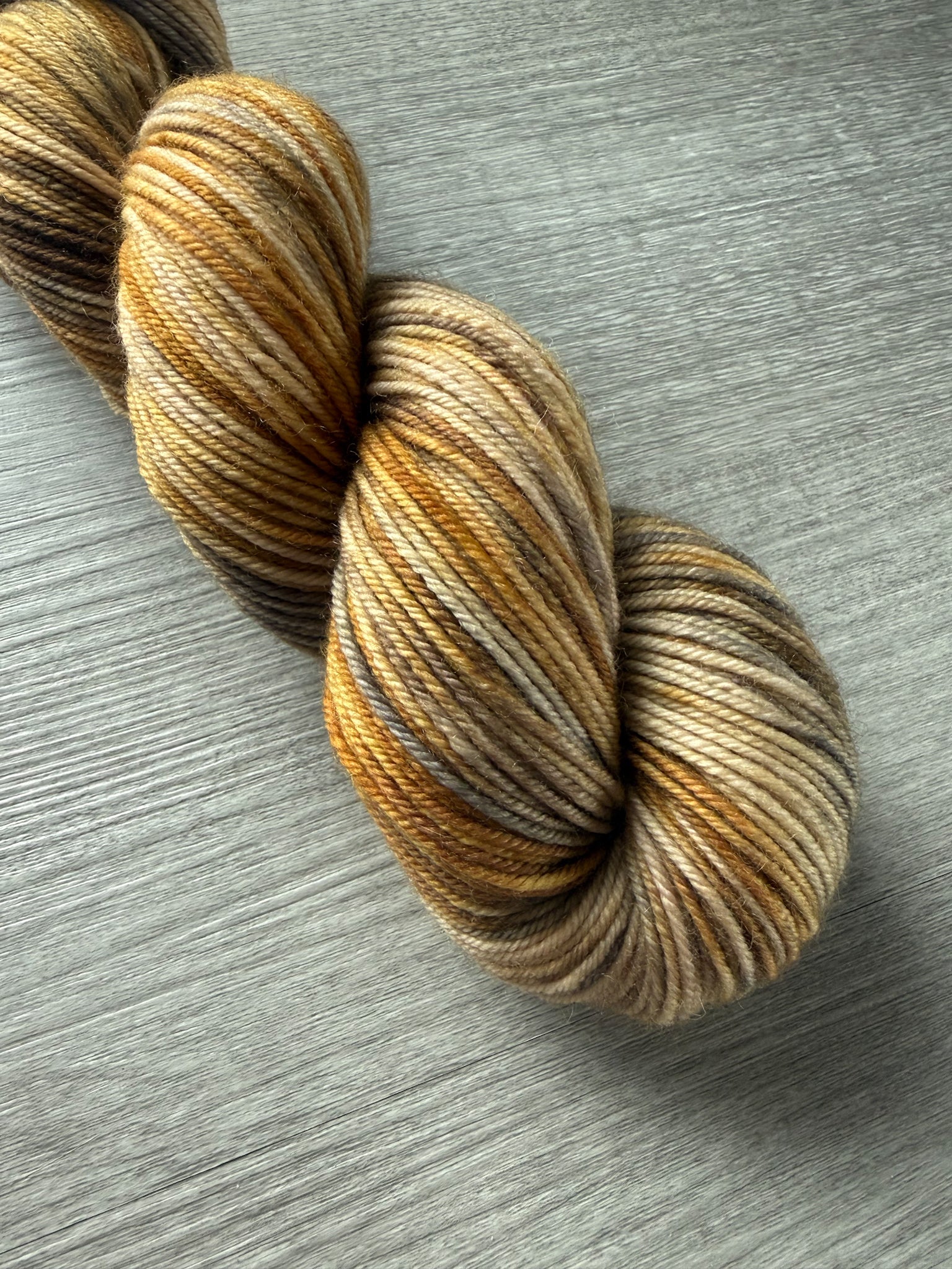 Hand-dyed Mesa merino wool yarn in variegated beige, charcoal, taupe, and toasted ocher. Ethically sourced.