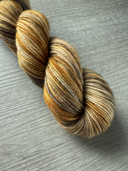 Hand-dyed Mesa merino wool yarn in variegated beige, charcoal, taupe, and toasted ocher. Ethically sourced.