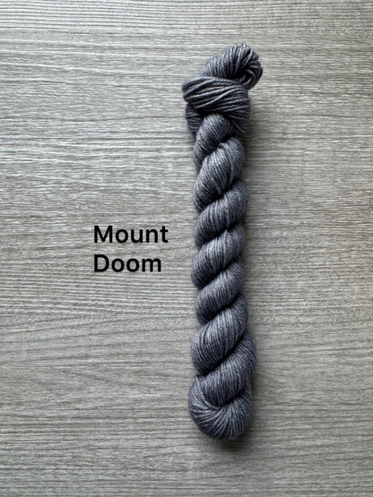 Gray skein of yarn labeled 'Mount Doom' on a wooden surface