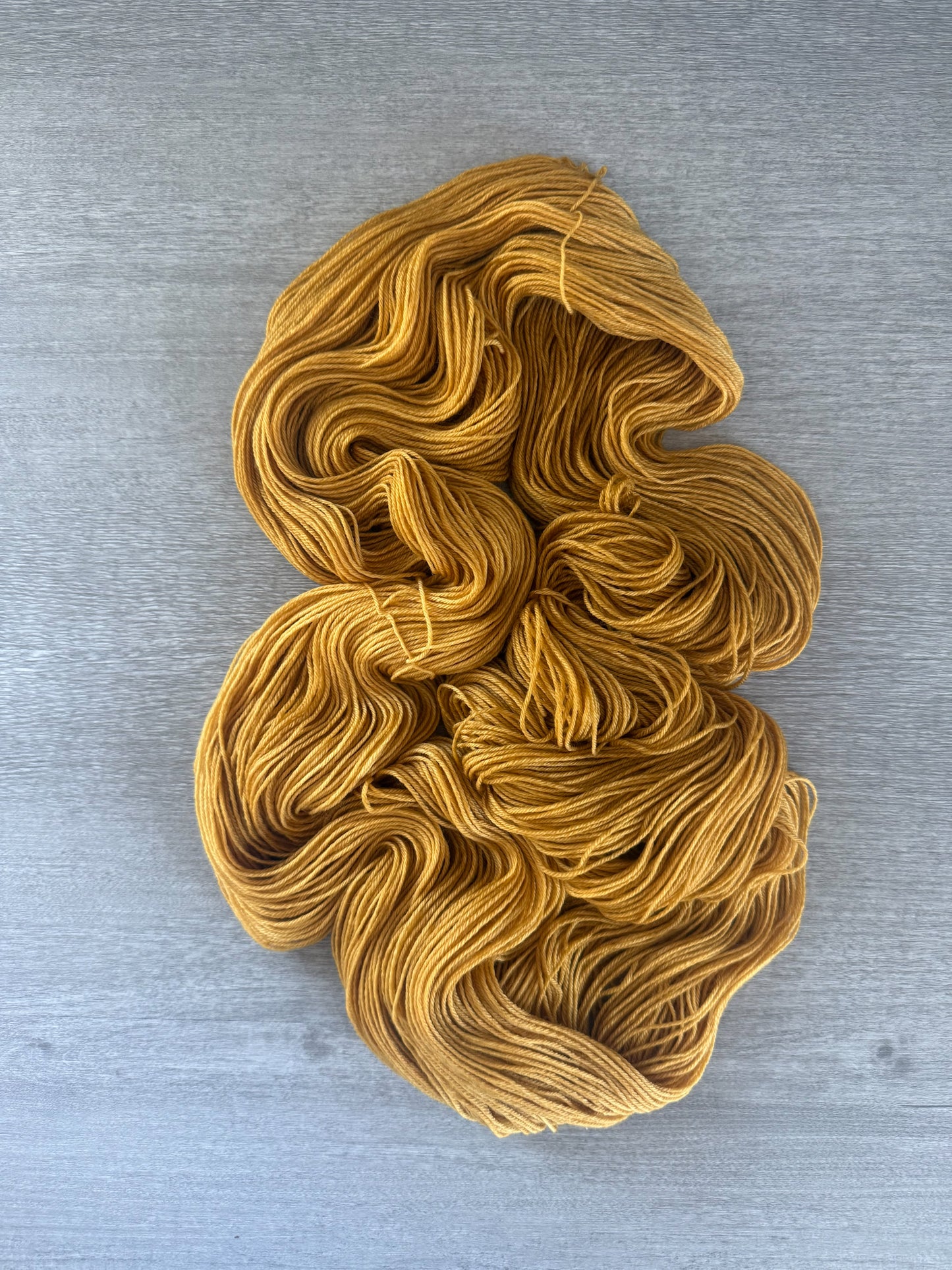 Hand-dyed "None Of Your Beeswax" golden yellow merino wool yarn, ethically sourced.