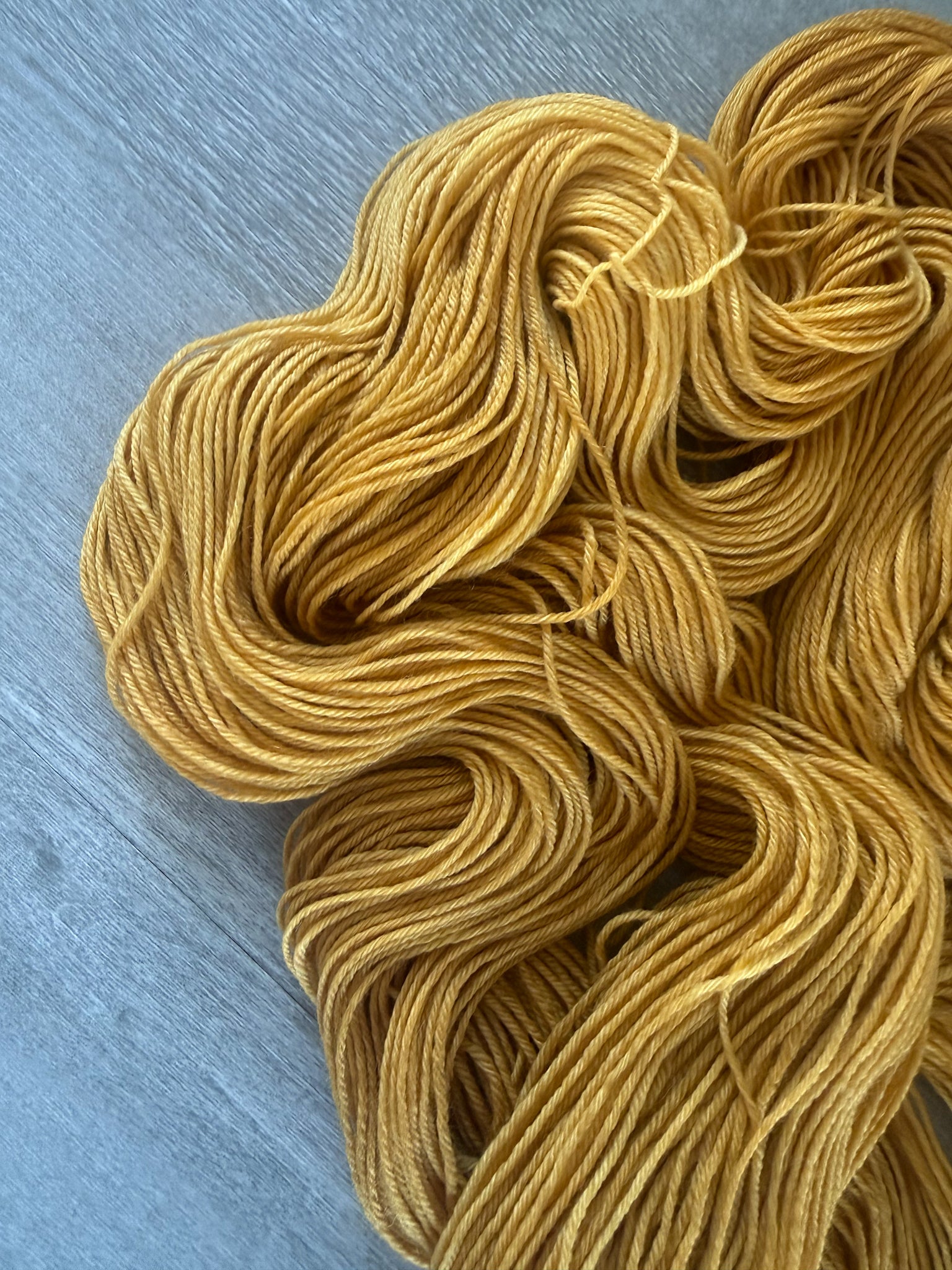 Hand-dyed "None Of Your Beeswax" golden yellow merino wool yarn, ethically sourced.