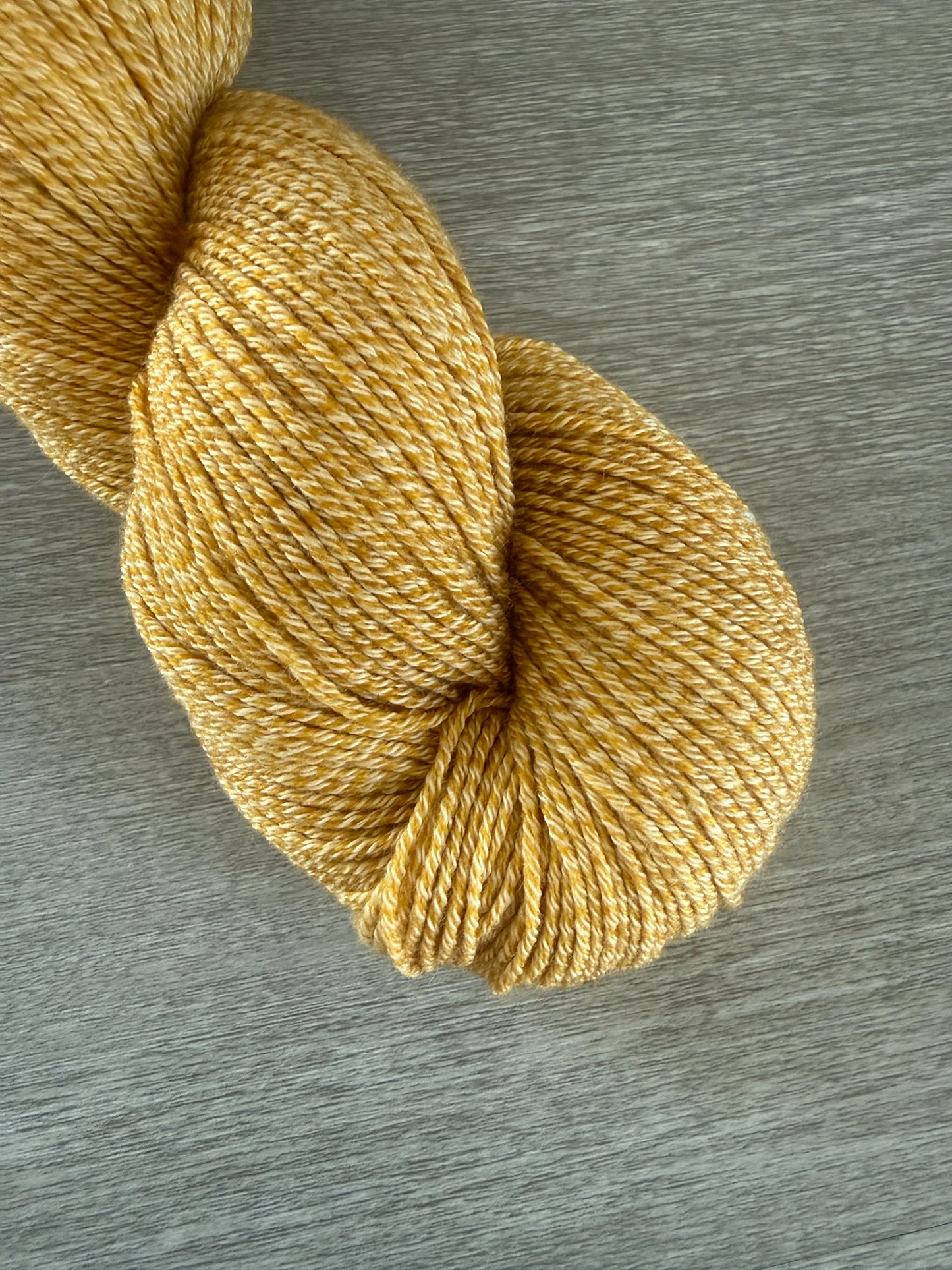 Hand-dyed "None Of Your Beeswax" golden yellow merino wool yarn skein.