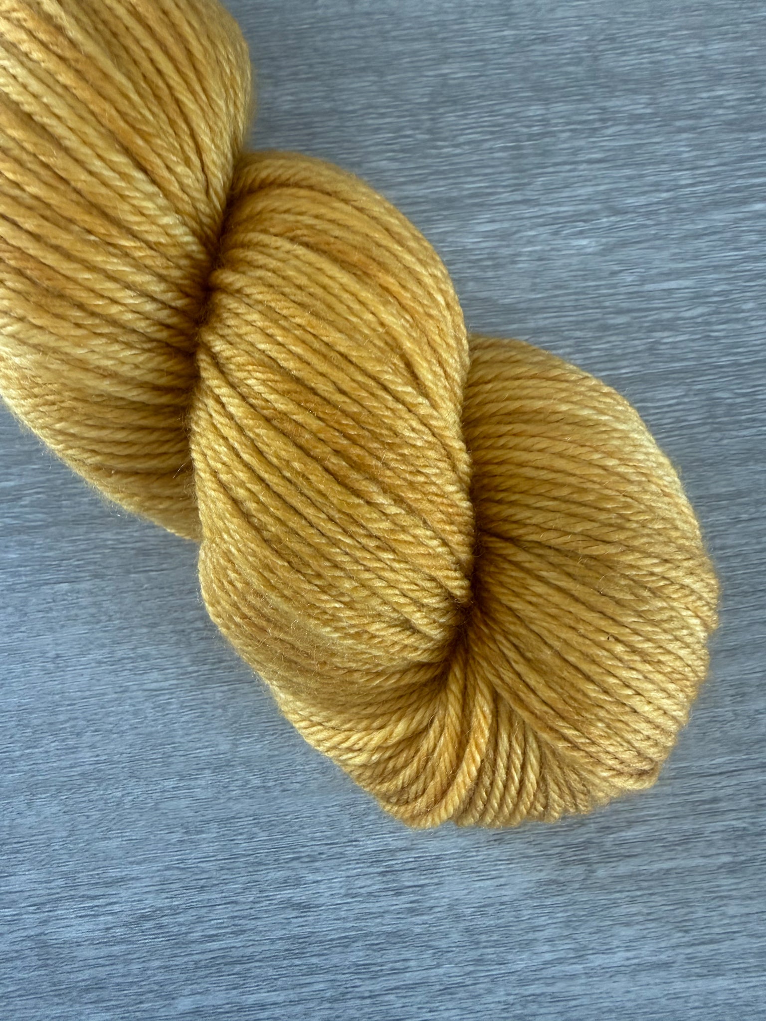 Hand-dyed "None Of Your Beeswax" golden yellow merino wool yarn skein.