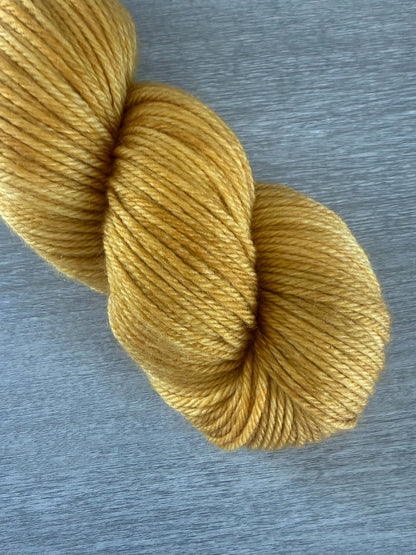 Hand-dyed "None Of Your Beeswax" golden yellow merino wool yarn skein.