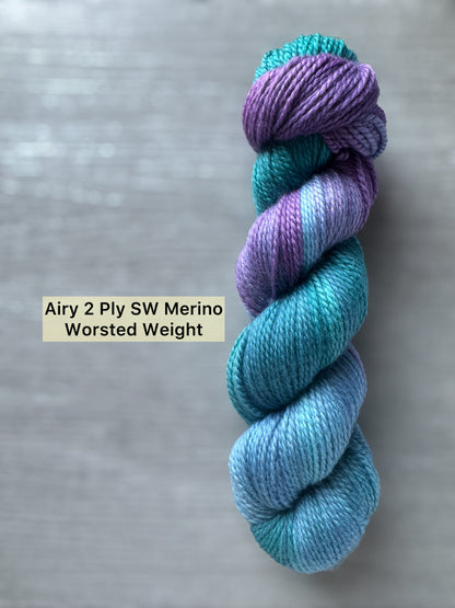Blue and purple yarn skein on a gray background with text label.