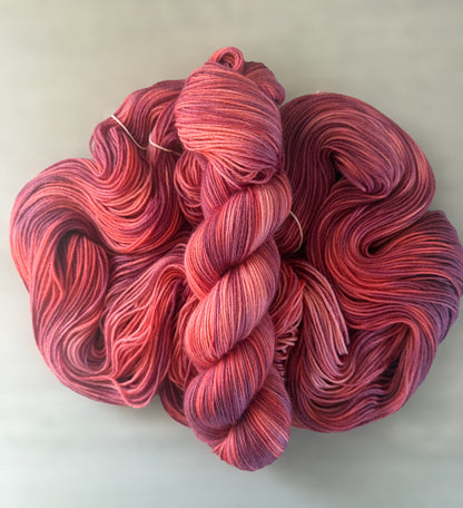 Ethically sourced Summer Fling merino wool yarn, hand-dyed in variegated burgundy, red, and orange hues.