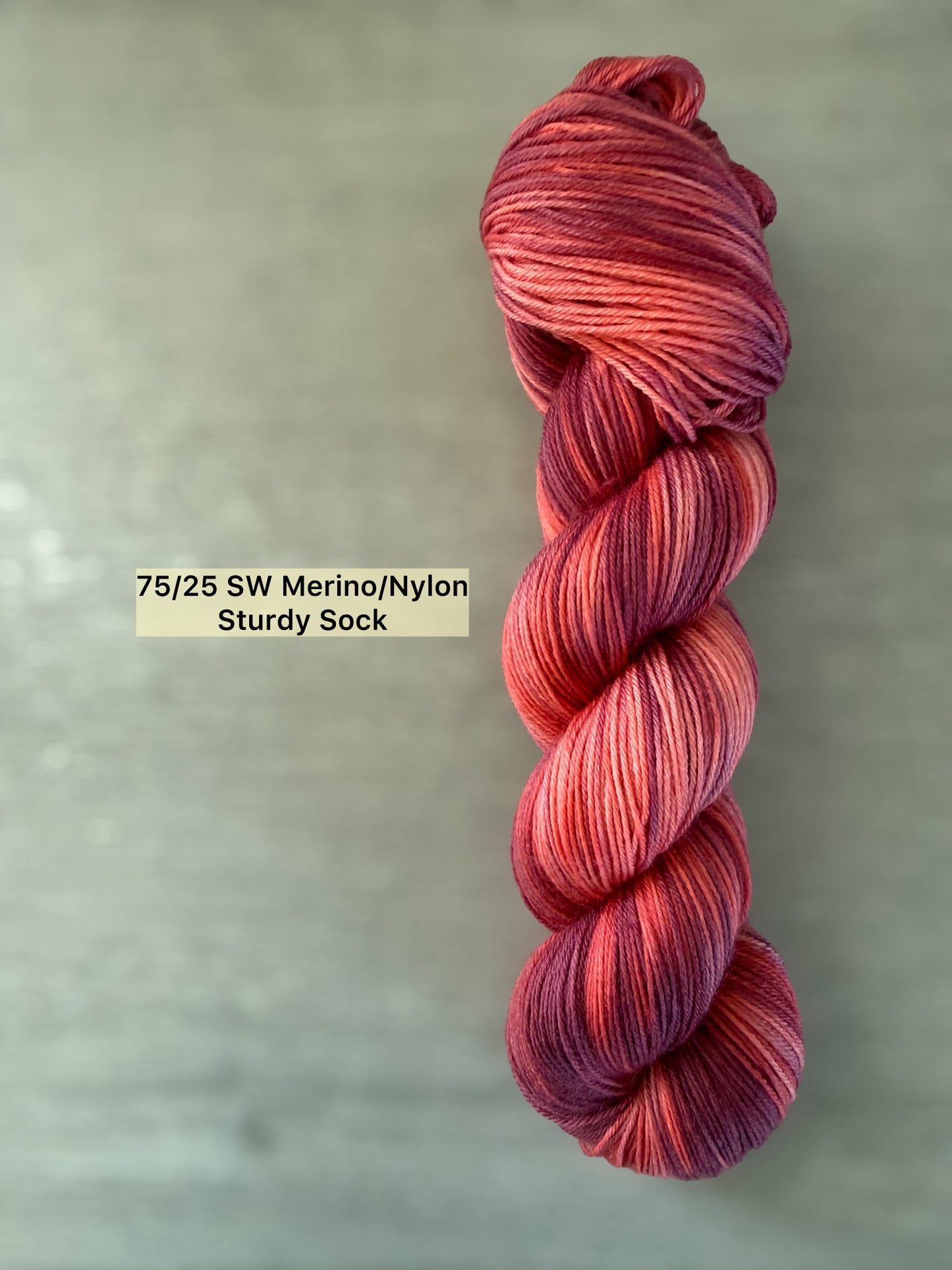 Ethically sourced "Summer Fling" variegated merino wool yarn in burgundy, red, and orange sunset hues.
