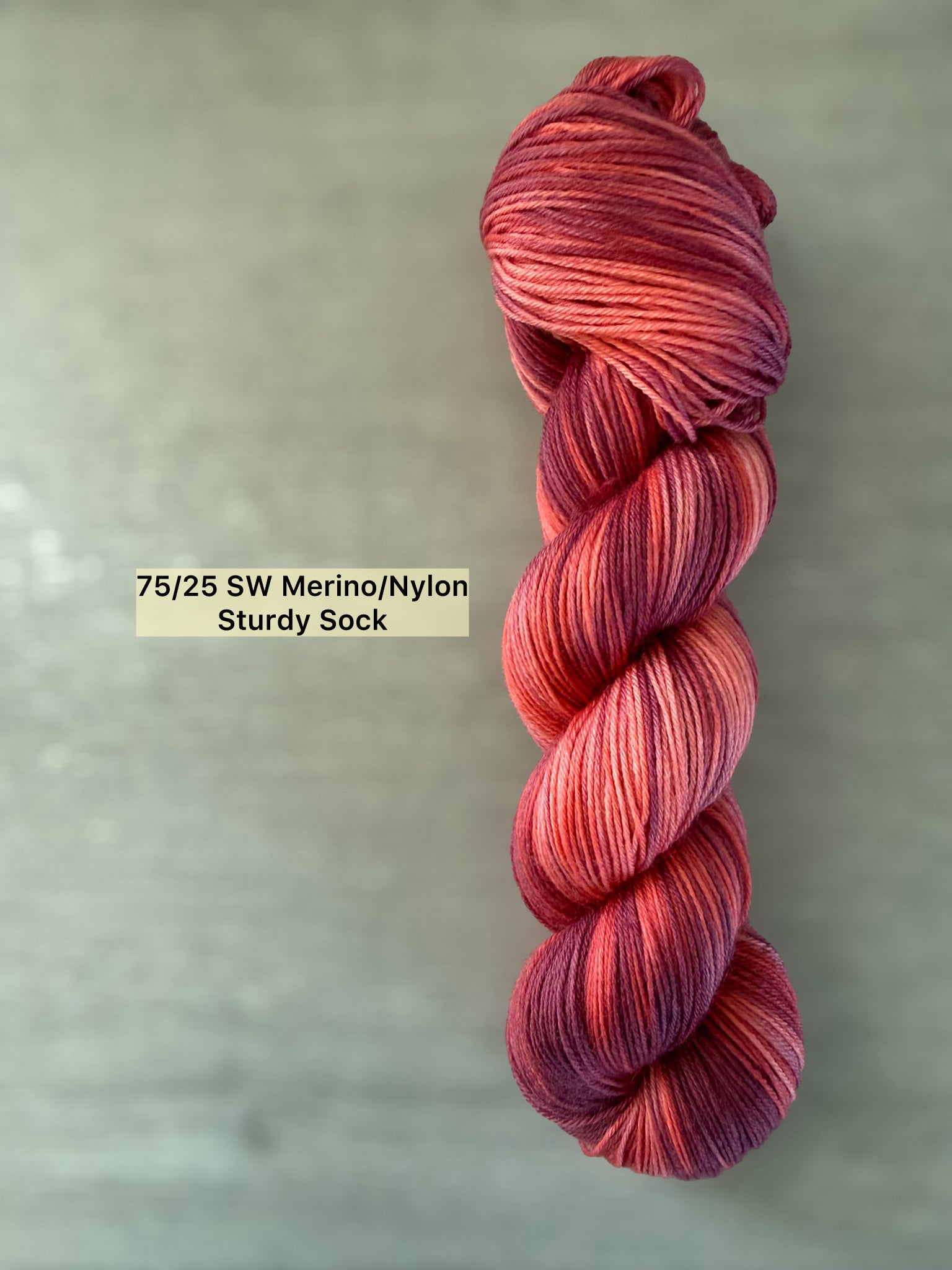 Ethically sourced "Summer Fling" variegated merino wool yarn in burgundy, red, and orange sunset hues.