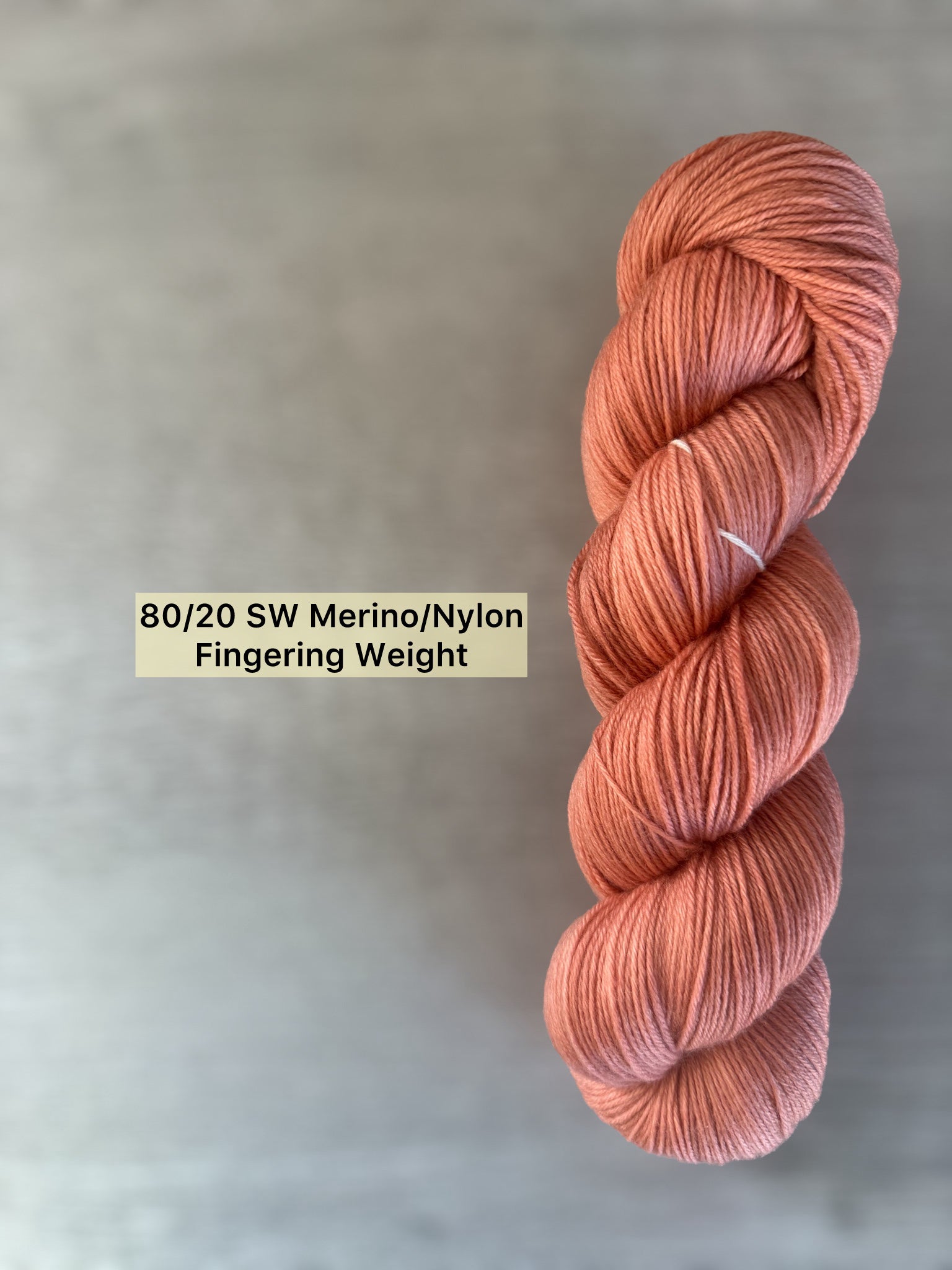 Terracotta hand-dyed ethically sourced merino wool yarn, fingering weight, with warm reddish-brown tones.