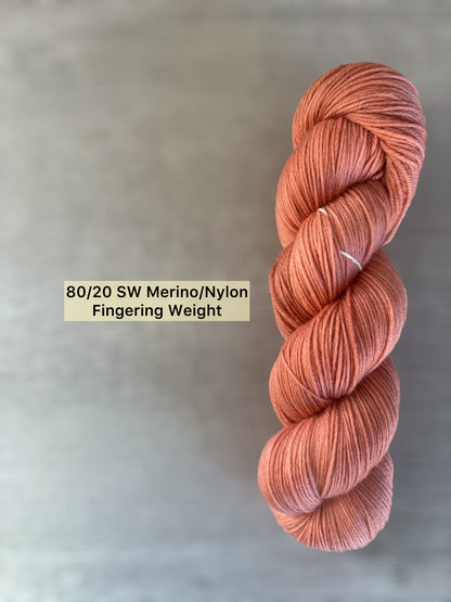 Terracotta hand-dyed ethically sourced merino wool yarn, fingering weight, with warm reddish-brown tones.