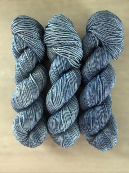 Three skeins of West Bay artisan hand-dyed ethically sourced merino wool yarn in serene blue tonal shades.