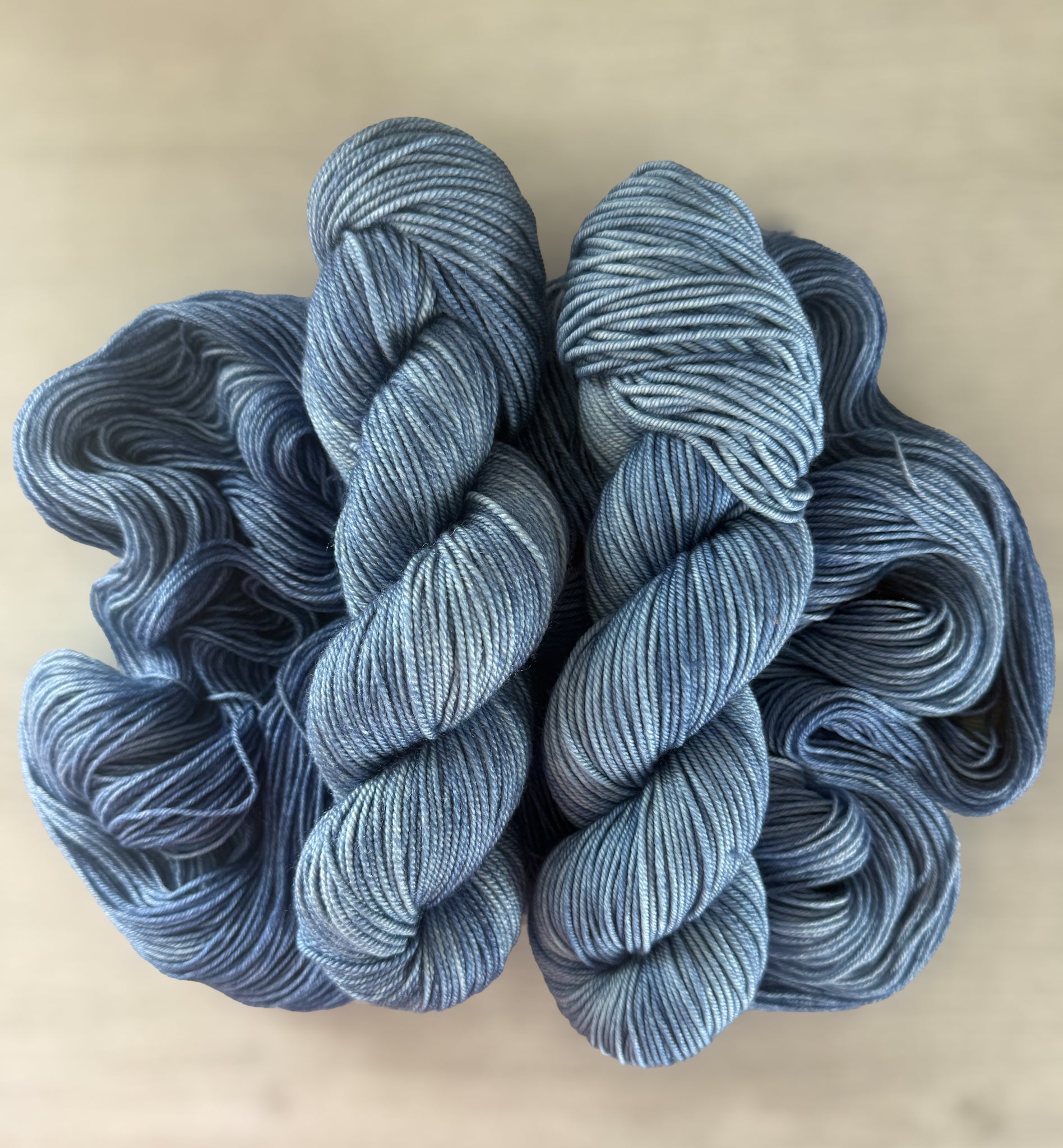 Two skeins of West Bay hand-dyed ethically sourced merino wool yarn in serene blue tonal shades.