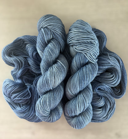 Two skeins of West Bay hand-dyed ethically sourced merino wool yarn in serene blue tonal shades.