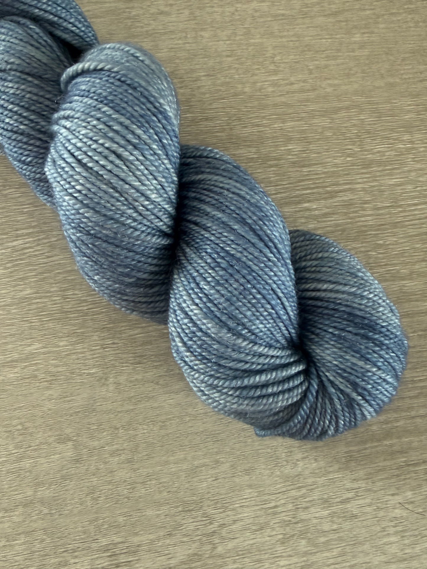Hand-dyed "West Bay" artisan merino wool yarn in serene blue tonal shades, ethically sourced.