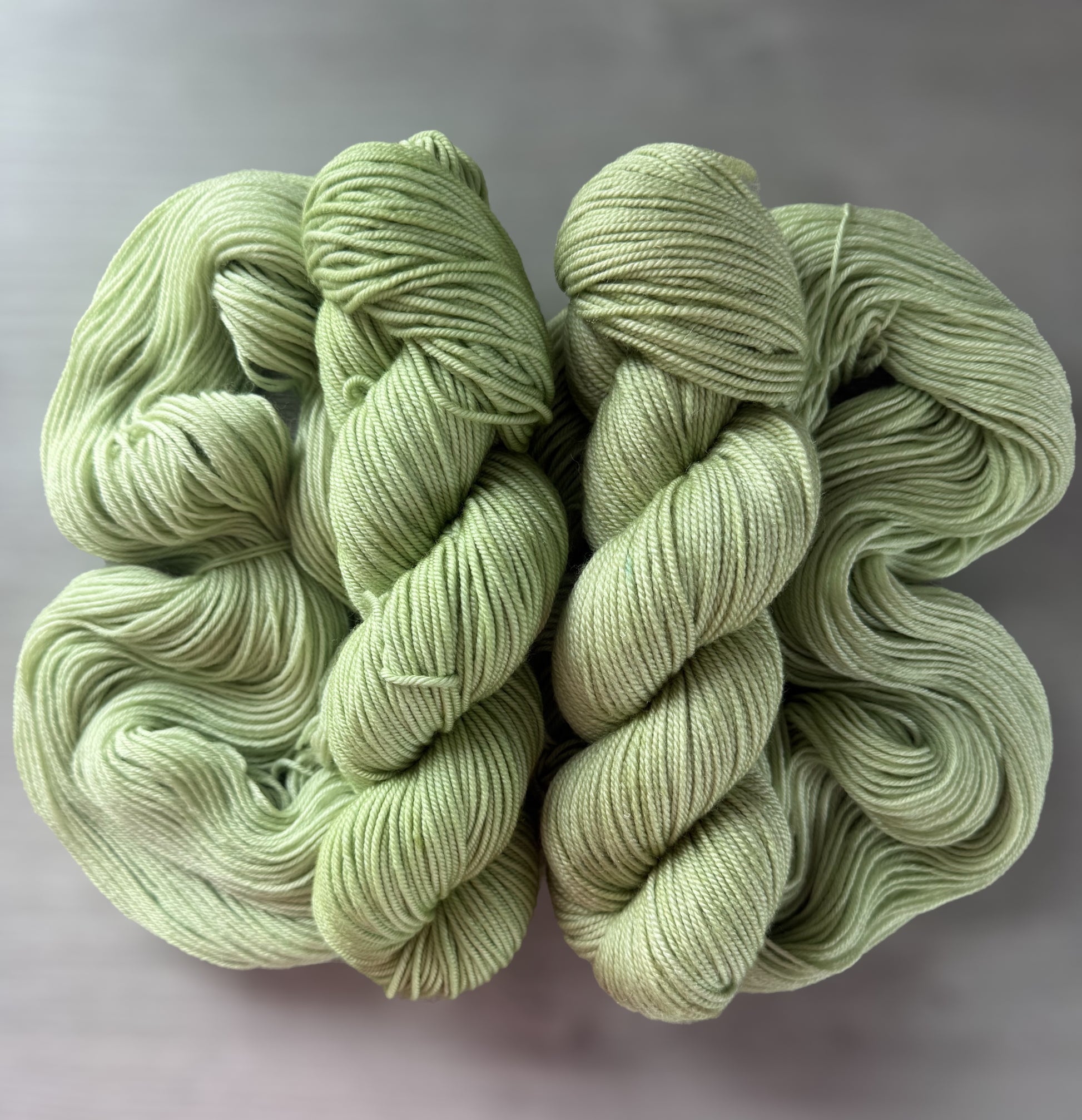 Two skeins of "Too Many Margaritas" vibrant lime green hand-dyed ethically sourced merino wool yarn.