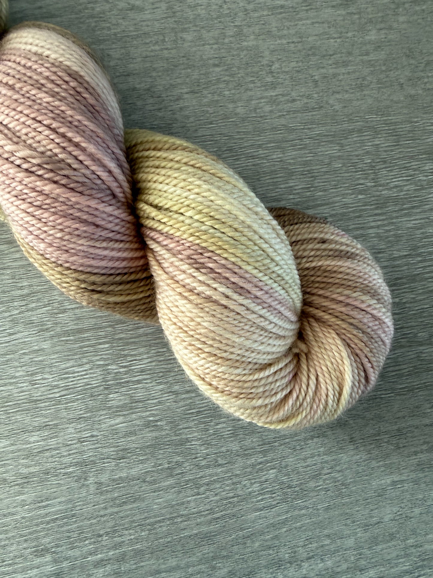Ethically sourced merino wool yarn in dusty pink, golden yellow, and light tan watercolor shades.