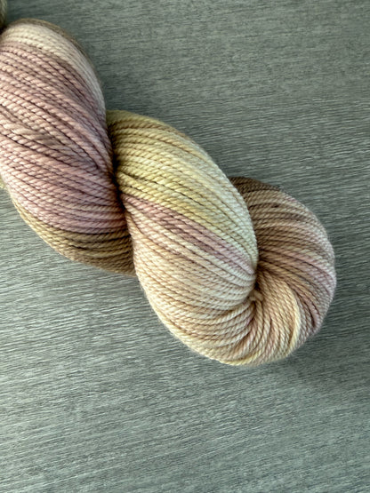 Ethically sourced merino wool yarn in dusty pink, golden yellow, and light tan watercolor shades.
