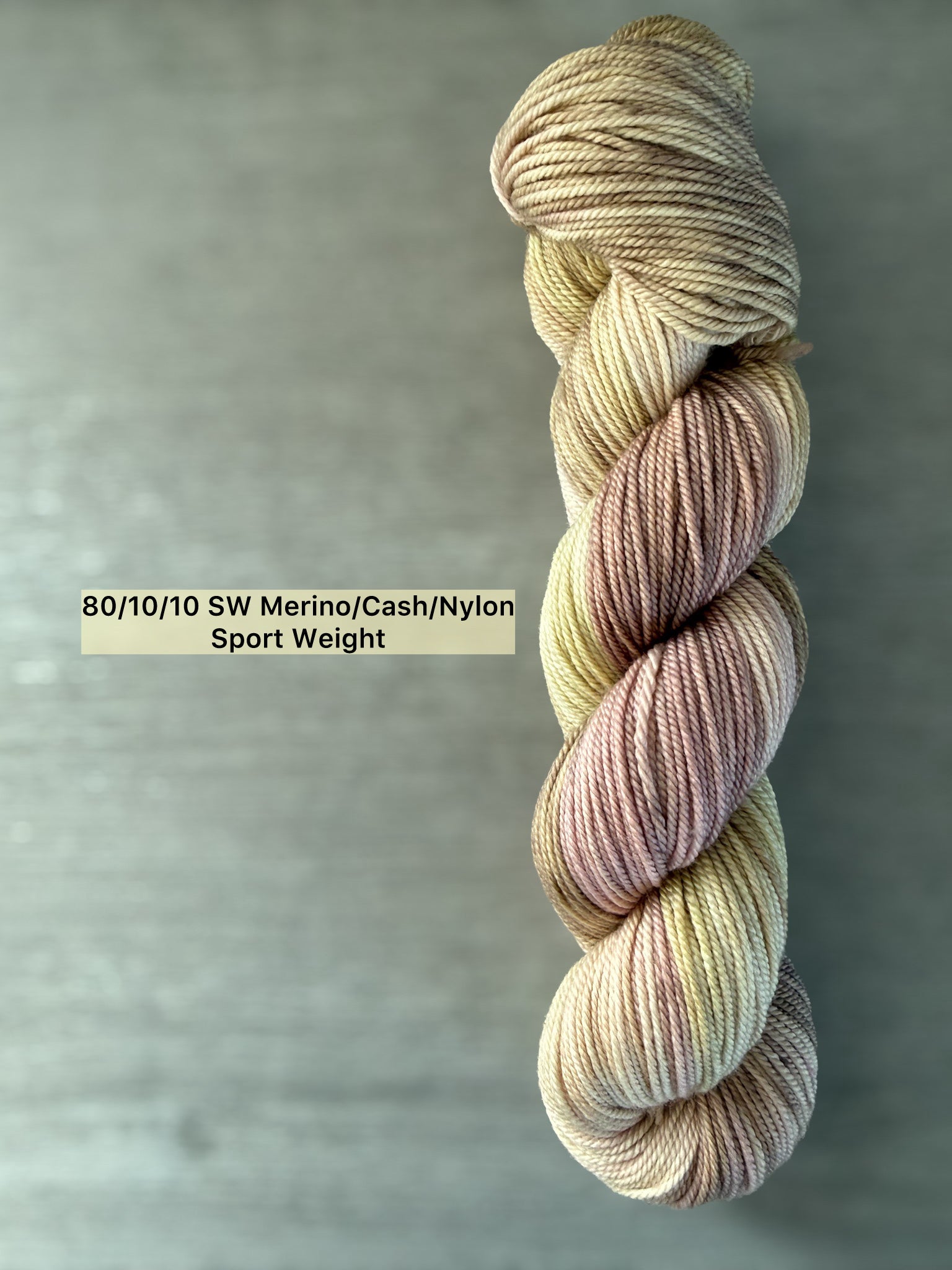 Ethically sourced merino wool yarn in soft dusty pink, golden yellow, and light tan watercolor hues.