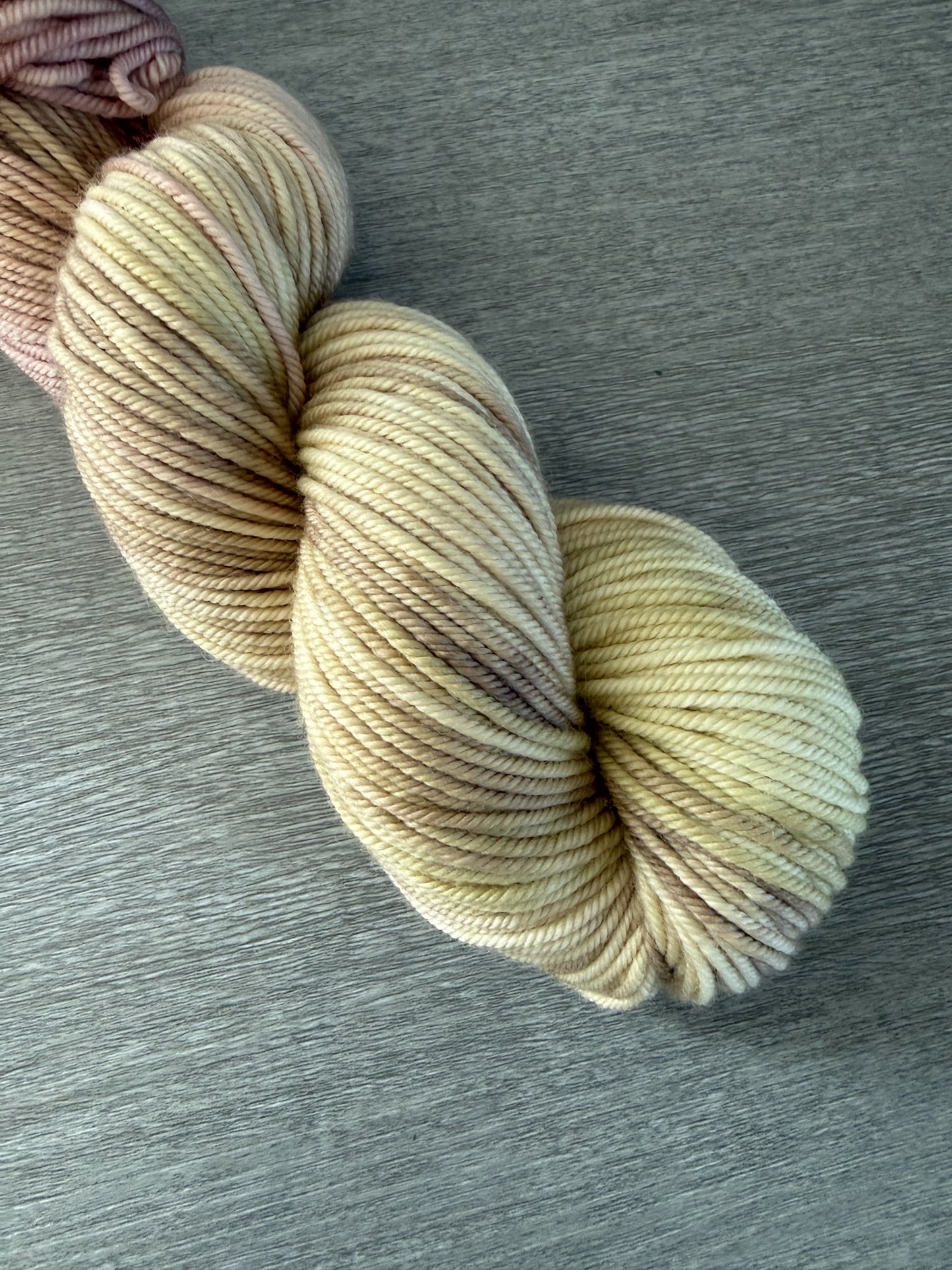 Ethically sourced merino wool yarn in dusty pink, golden yellow, and light tan watercolor hues.